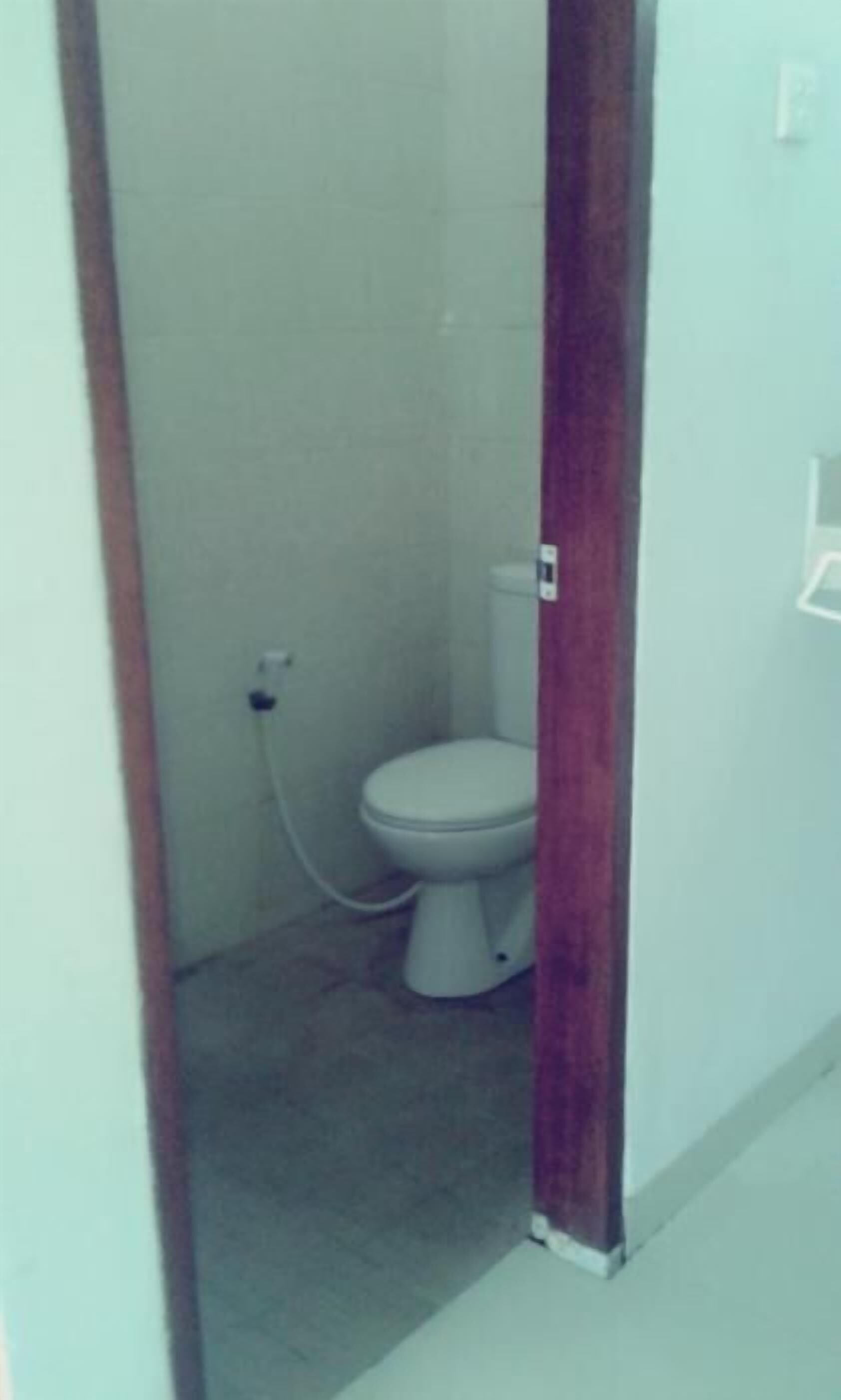 Ein kleines, schmales Badezimmer mit Toilette, einem sichtbaren Stromanschluss und einer Holzsäule.