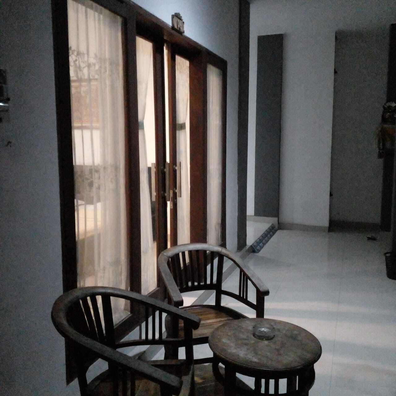 Een kamer met een schuifdeur, twee houten stoelen en een kleine ronde tafel.