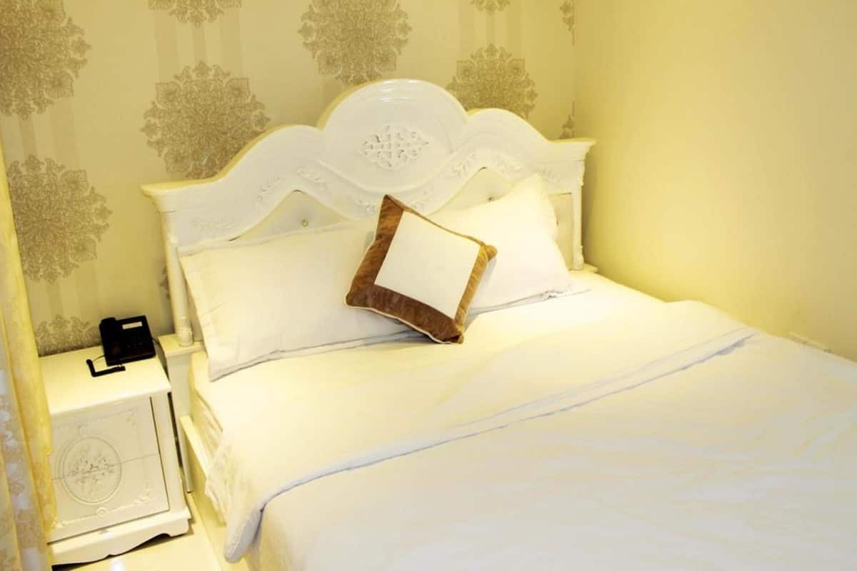 Cama bem arrumada com lençóis brancos e cabeceira decorativa.