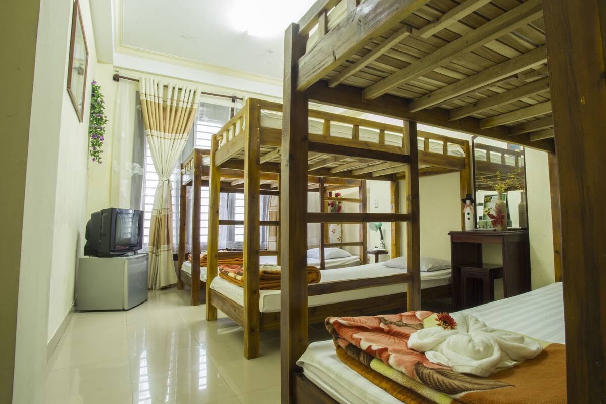 A room with bunk beds, a desk, a chair, a television, and a mirror.