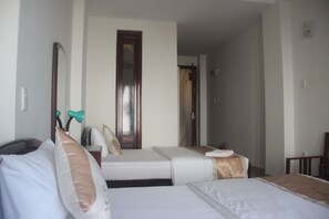 Una camera d'albergo con due letti, uno specchio, una porta e un tavolino.