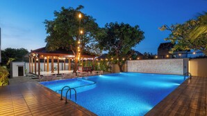A swimming pool with a wooden deck, a covered seating area, and a decorative wall. -  Aston Inn Rembang  (Rembang)