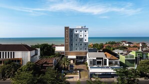 A hotel with a prominent 'Aston' sign, surrounded by other buildings, with a view of the sea. -  Aston Inn Rembang  (Rembang)