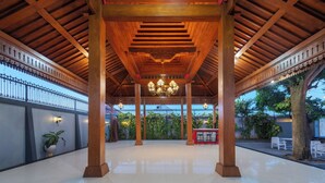 A covered outdoor area with a tiled floor, wooden pillars, and hanging lights. -  Aston Inn Rembang  (Rembang)