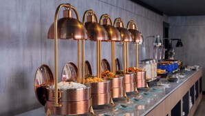 A buffet setup with copper serving containers and gold handles, arranged on a marble countertop. -  Aston Inn Rembang  (Rembang)