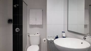 Un baño moderno con inodoro, lavamanos y ducha.