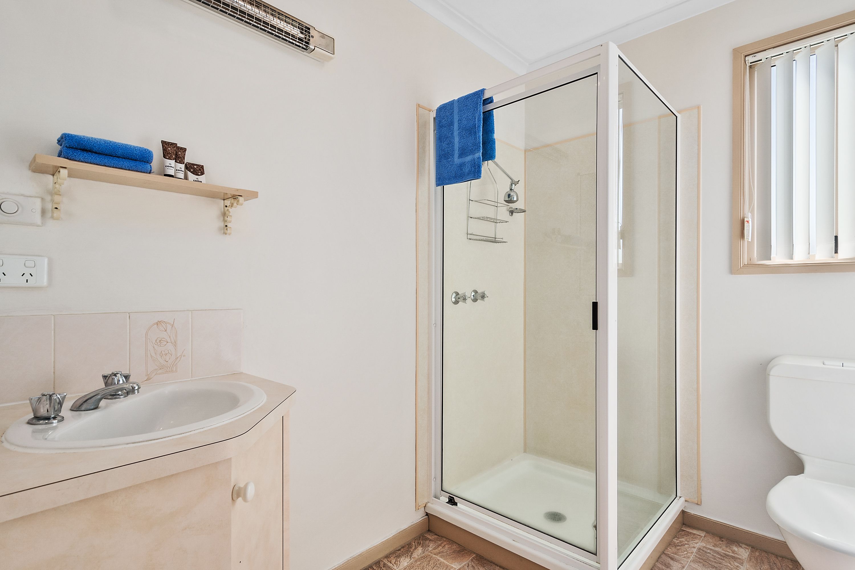 A bathroom with a glass-enclosed shower, a sink, and a toilet.