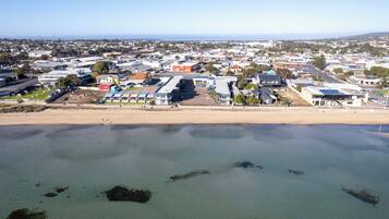 An aerial view of a coastal town with buildings, a beach, and clear skies.