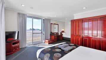 A hotel room with a large bed, a TV, a desk, and a wardrobe.
