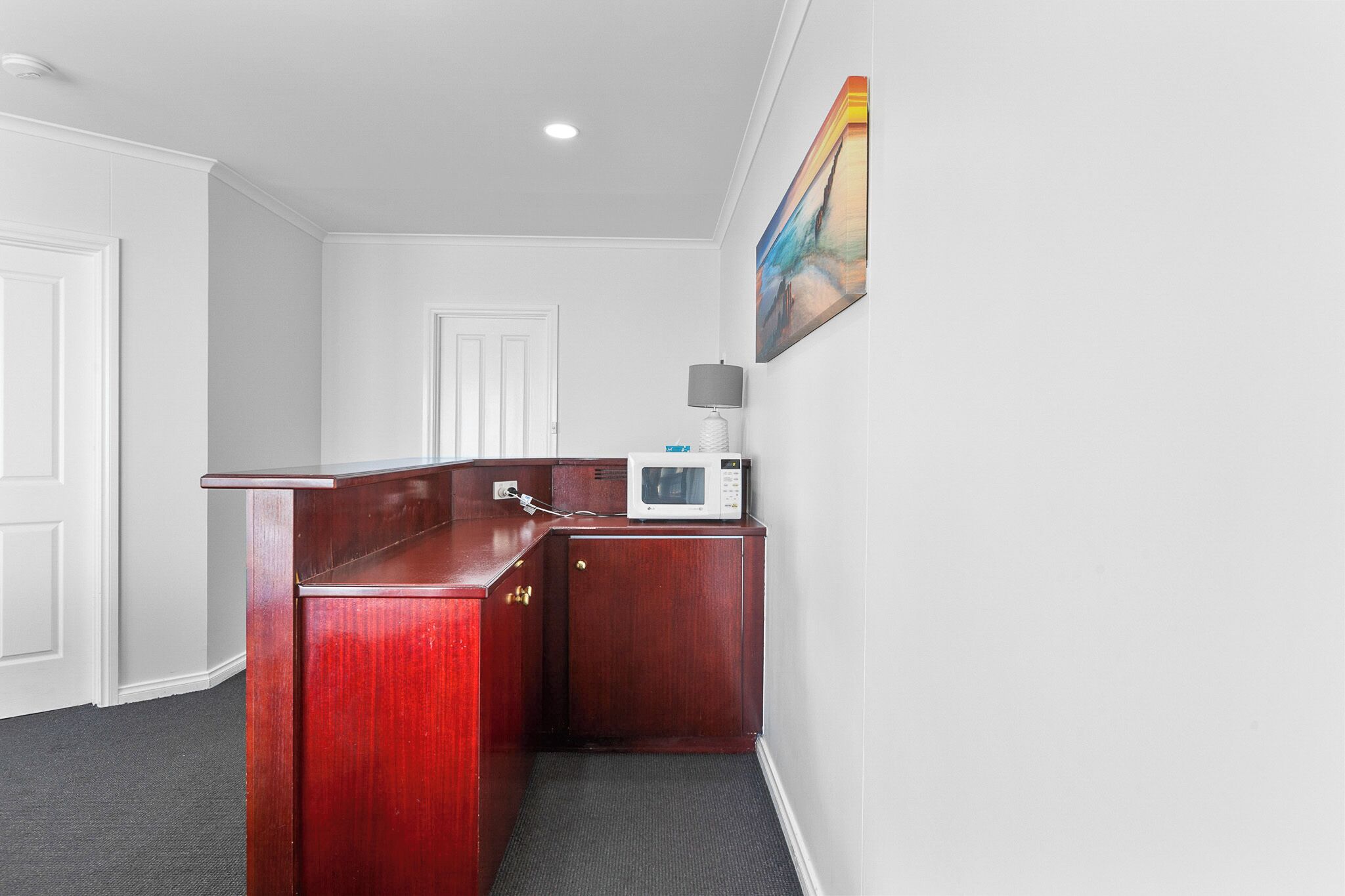 A small, compact kitchen area with a microwave, a cabinet, and a door.