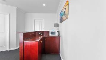 A small, compact kitchen area with a microwave, a cabinet, and a door.