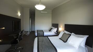 Habitación de hotel con dos camas, un escritorio, una silla, un televisor y una lámpara en el techo.
