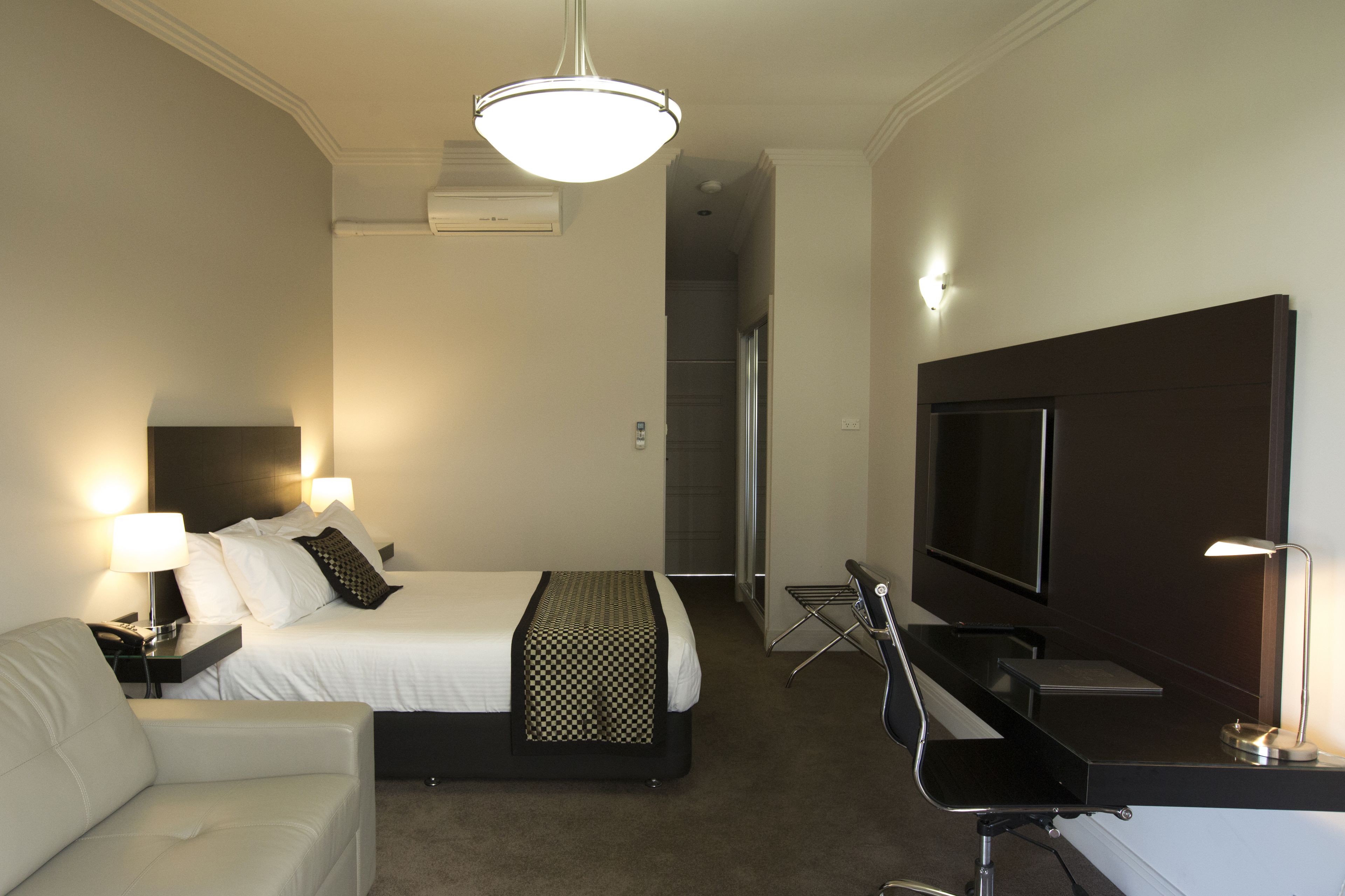 A hotel room with a bed, a desk, a television, and a chair.