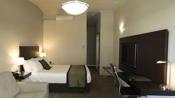 A hotel room with a bed, a desk, a television, and a chair.