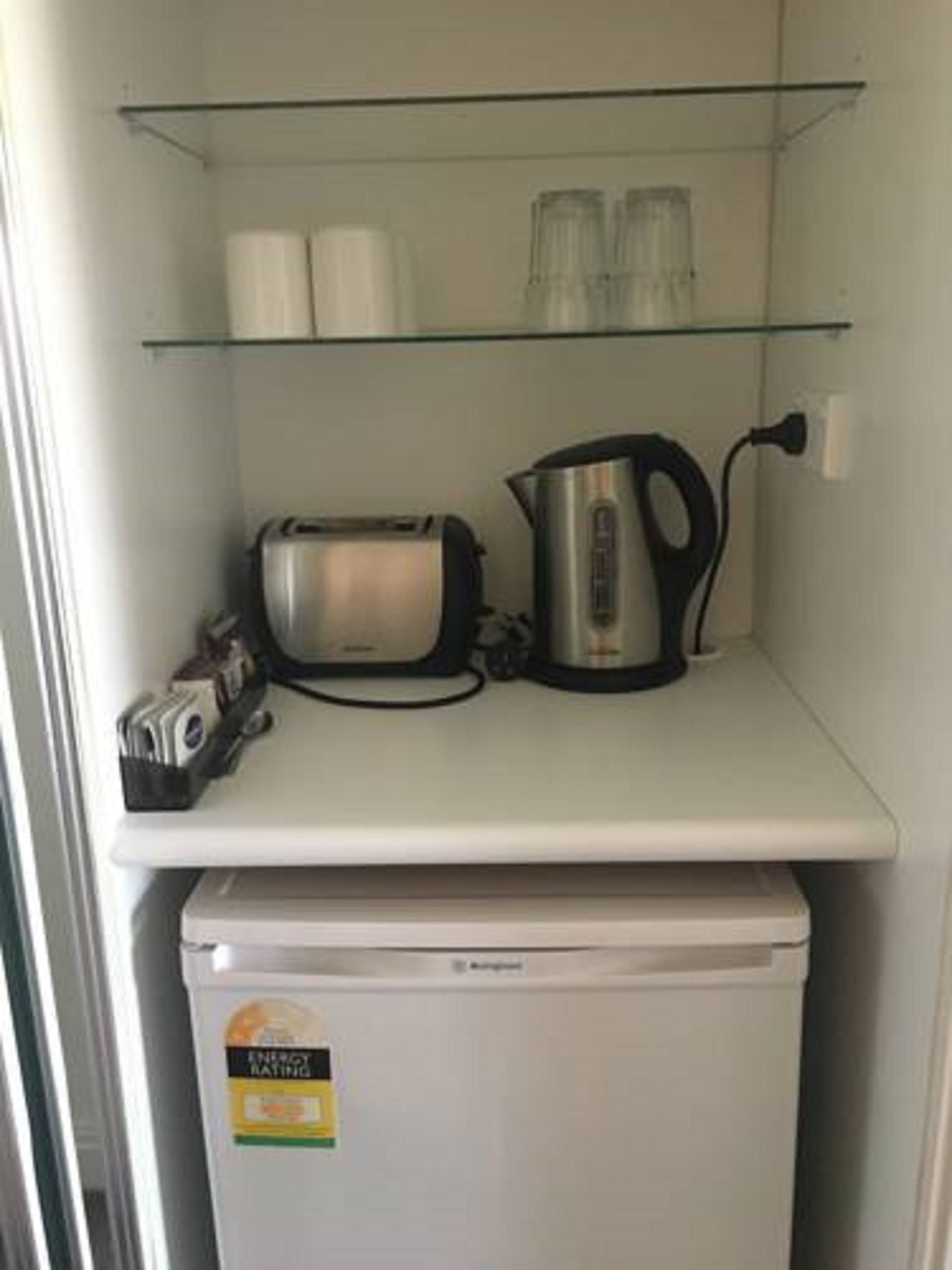 A kitchen with a toaster, kettle, and a small refrigerator.