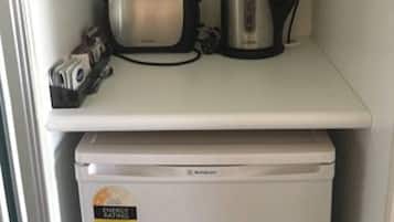 A kitchen with a toaster, kettle, and a small refrigerator.