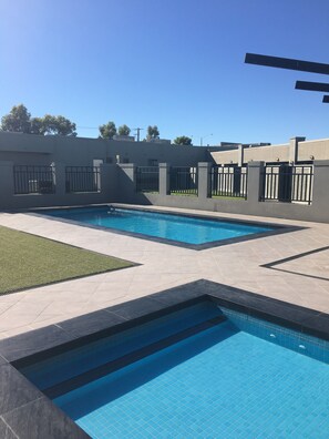 A swimming pool with tiled edges and a surrounding patio area.