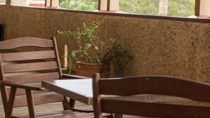 A covered outdoor seating area with wooden benches and a table, overlooking a palm tree and greenery. - Hydro Hotel (Leeton)