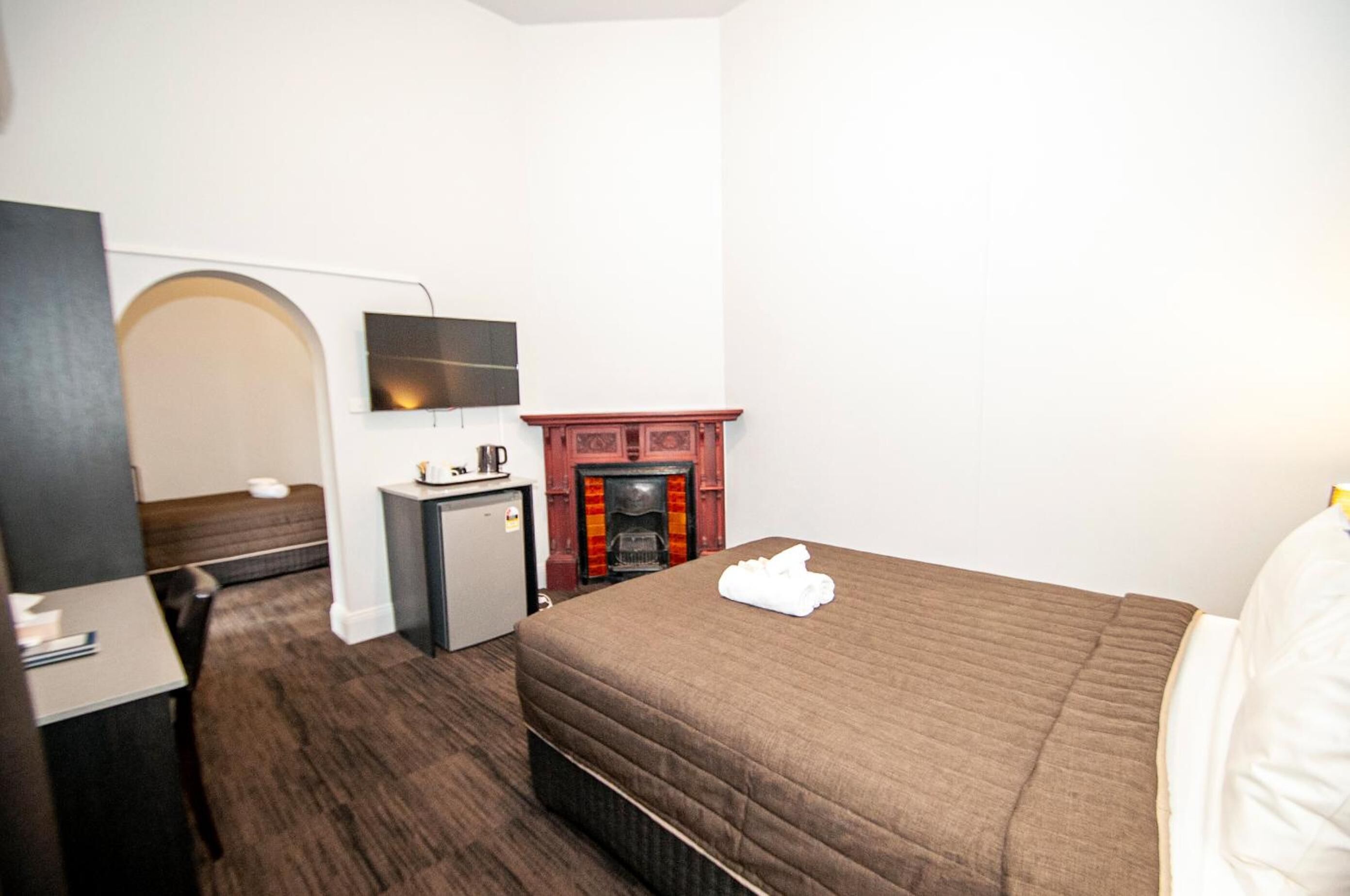 Une chambre d’hôtel équipée d’un lit, d’un bureau, d’une télévision, d’une cheminée et d’une porte en arc de cercle.
