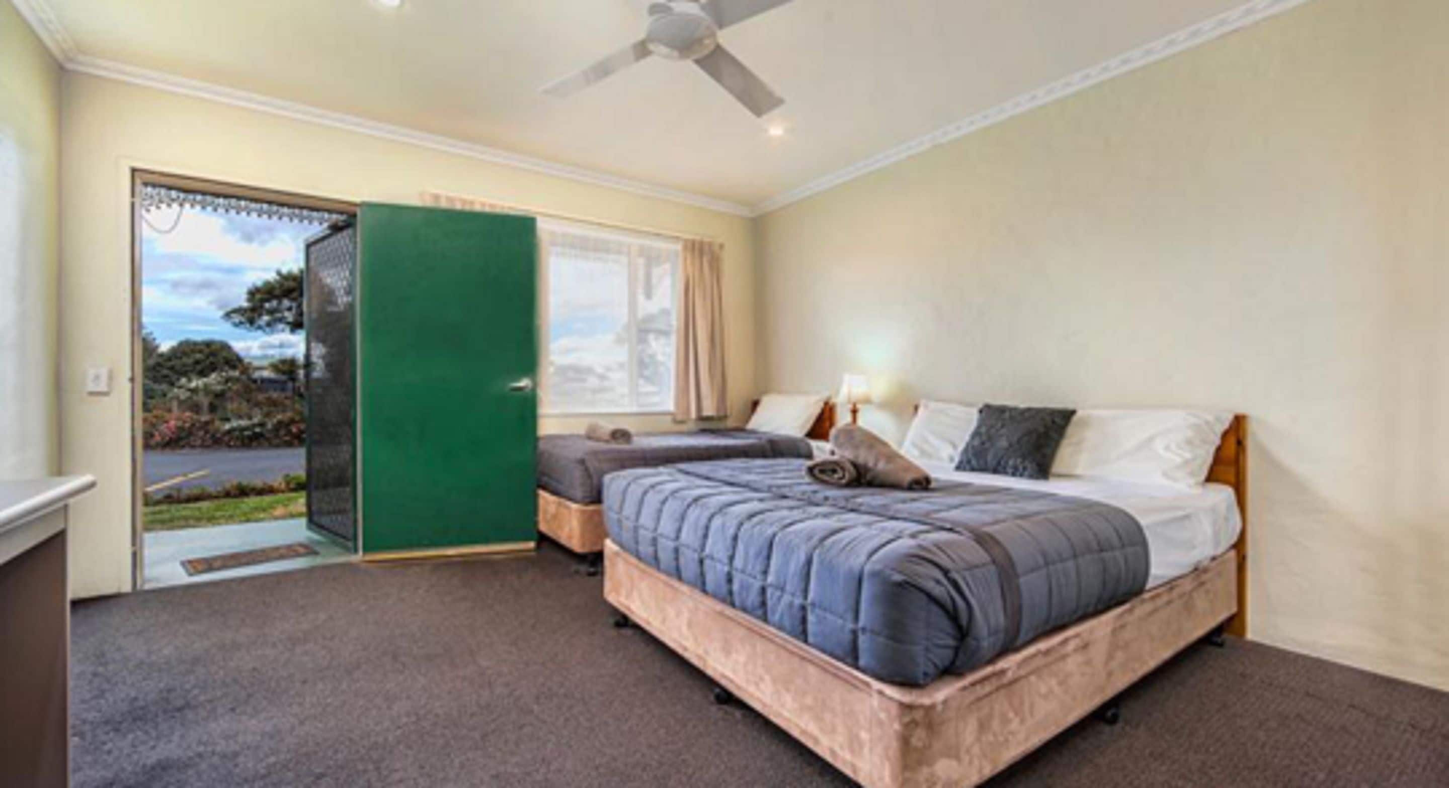 Un dormitorio con una cama, una puerta verde y vistas al exterior.