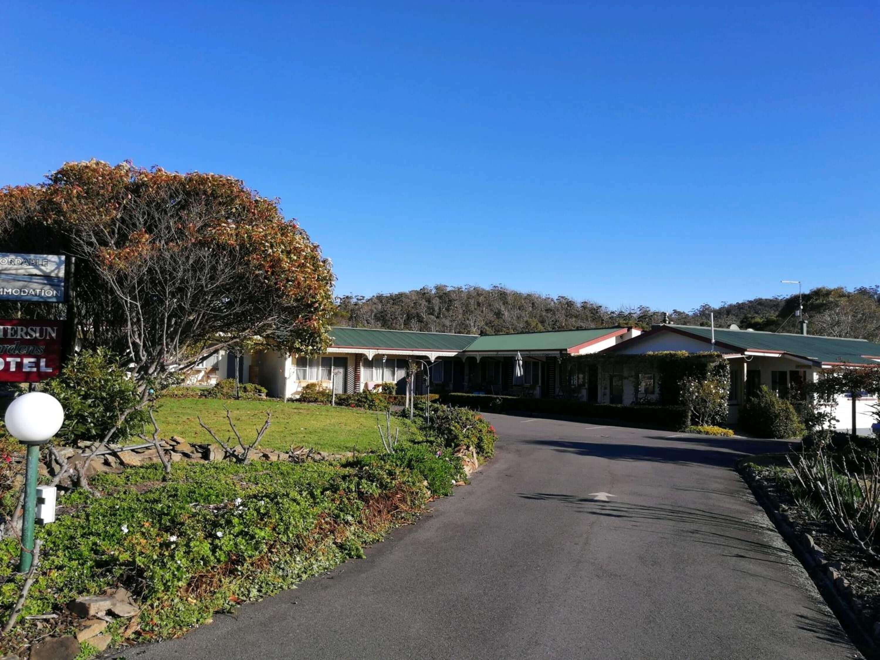 Un motel à deux étages, doté d’un toit végétalisé, entouré de verdure et surplombant un ciel dégagé.