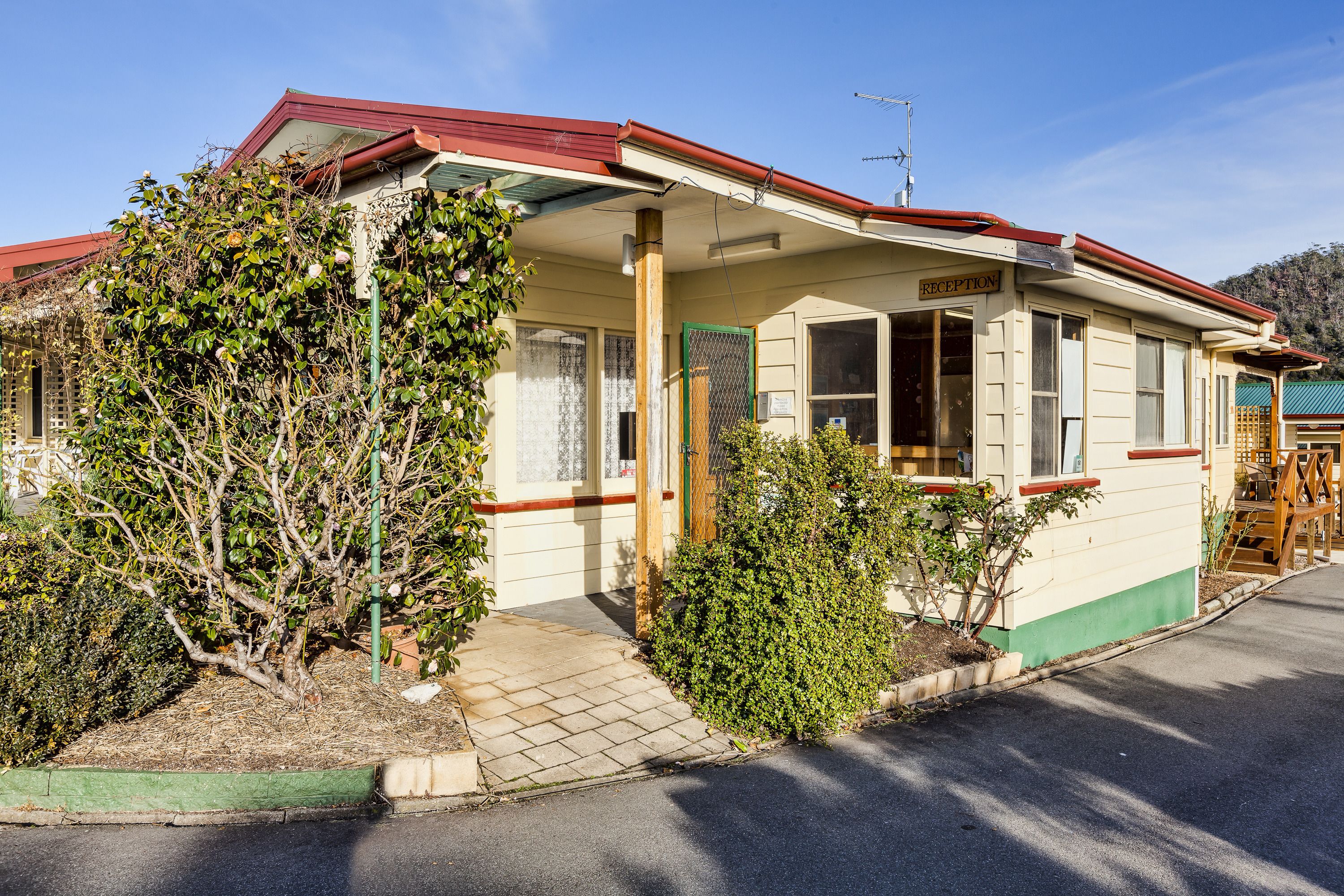 A single-story building with a reception area, a covered porch, and a small garden with shrubs and a tree.