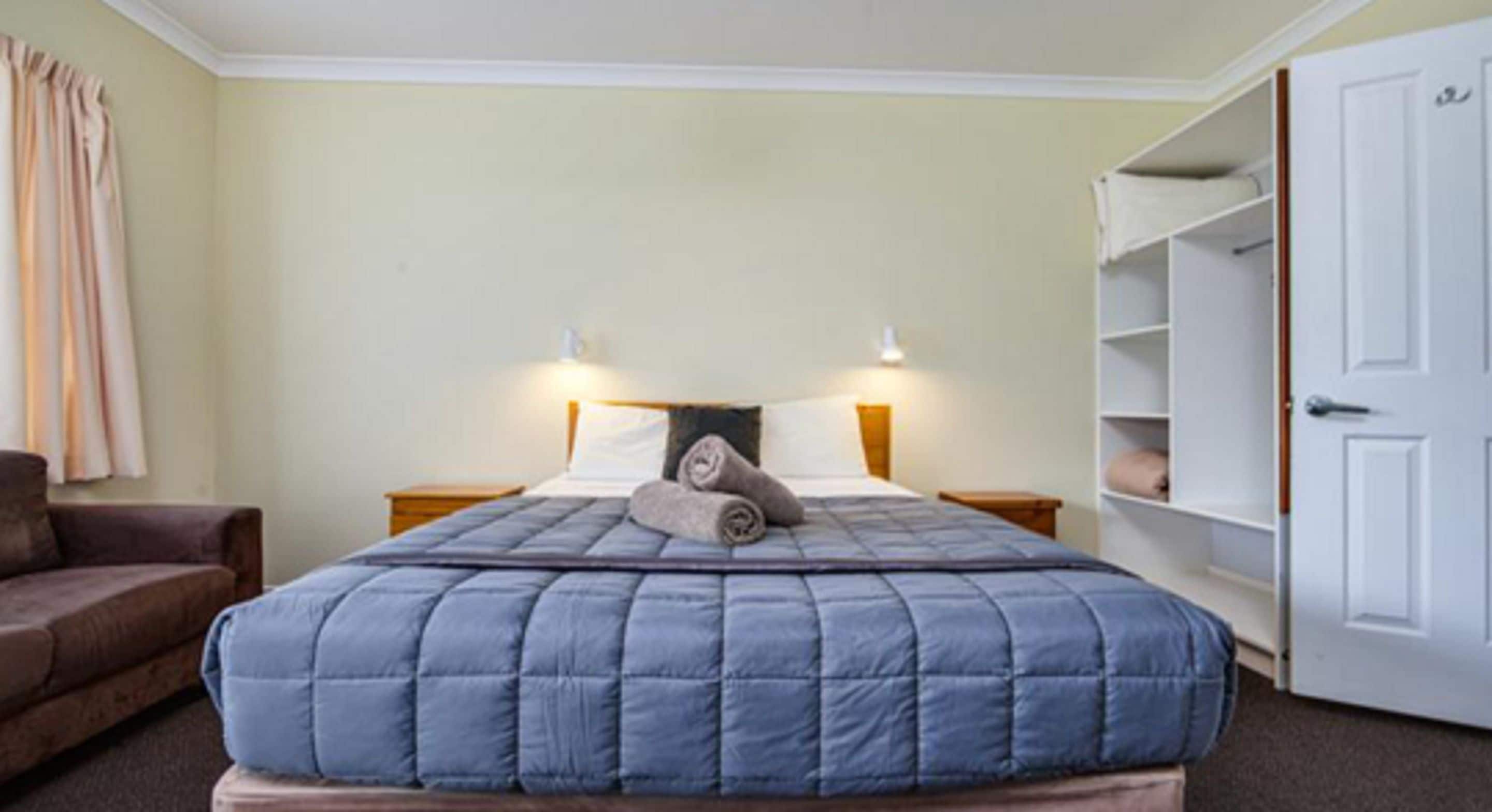 A bedroom with a bed, nightstands, a wardrobe, and a chair.