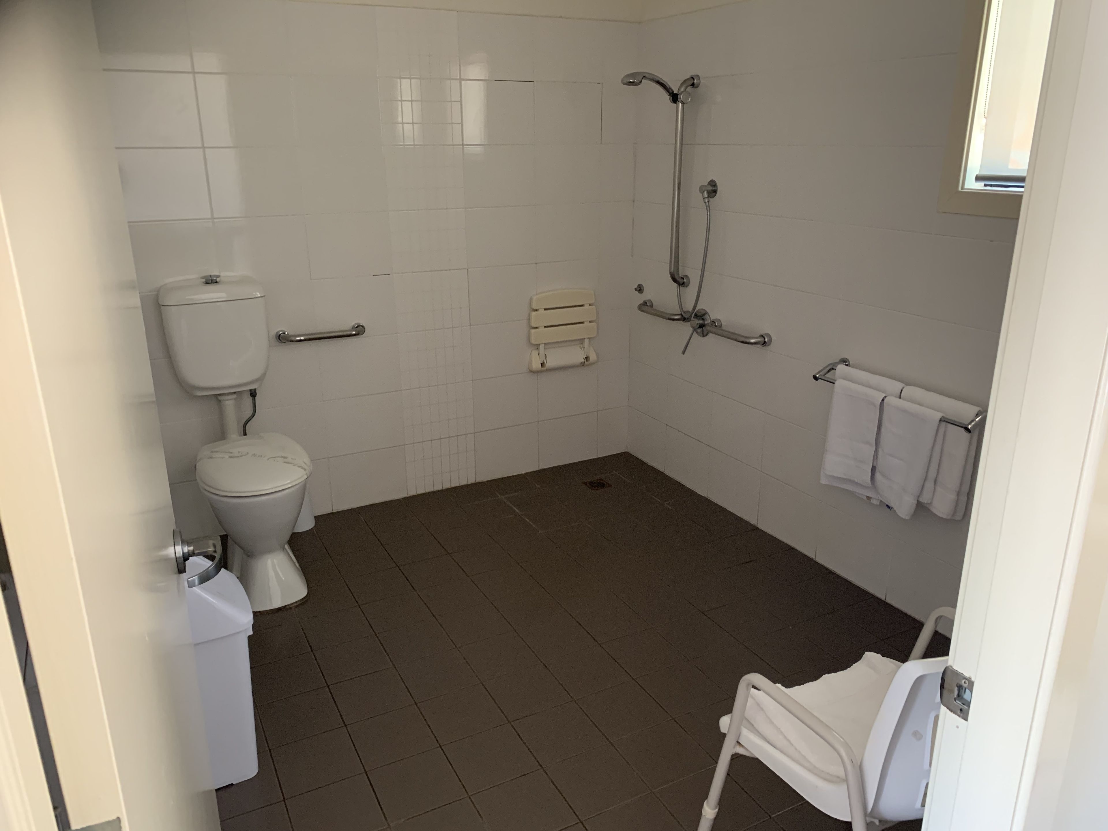 A bathroom with a toilet, a shower, and a hand dryer.
