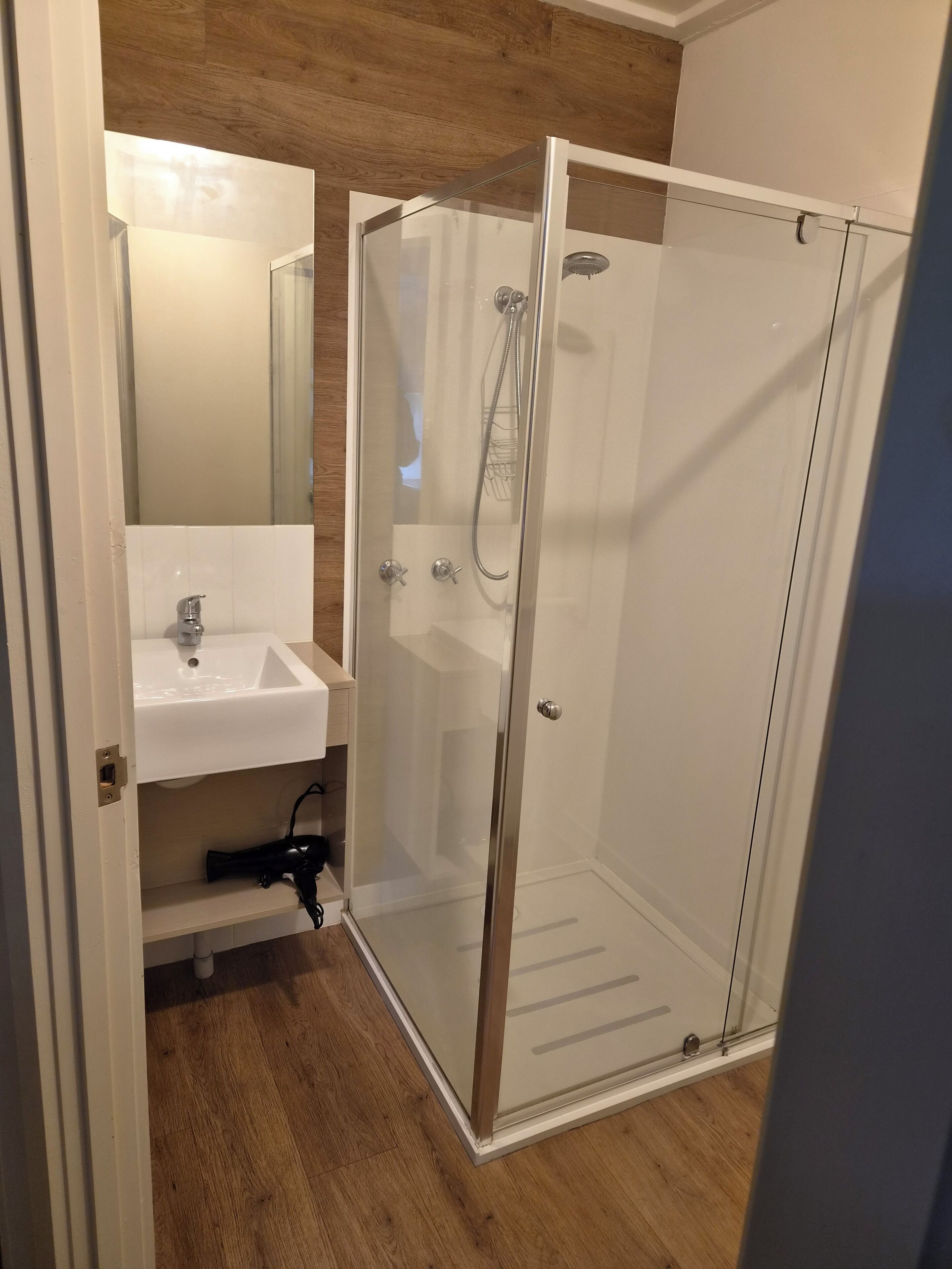 Une salle de bain avec une douche à parois de verre, un lavabo et un miroir.