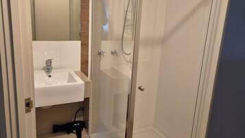 Une salle de bain avec une douche à parois de verre, un lavabo et un miroir.