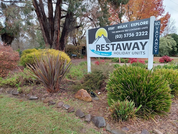 Une enseigne pour les logements de vacances RESTAWAY, avec un motif représentant une montagne et un soleil, située à Ovens River - Porepunkah, dans l'État de Victoria.
