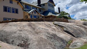 Uma casa grande, de vários andares, com alicerce de pedra, várias chaminés e um telhado imponente.