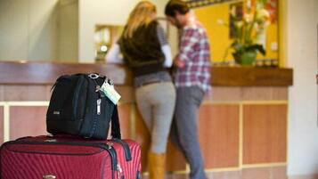 A reception area with a red suitcase and a black bag in the foreground.