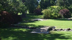 A well-maintained garden with a stone bridge, a pond, and various shrubs and trees. - Fountain Court Motor Inn Albury (Albury)