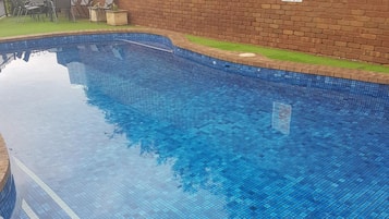 Una piscina al aire libre, sillones reclinables de piscina