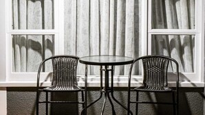 A window seat with two chairs and a table, set against a wall with three windows. - Frimley Lodge Motel (Hastings)
