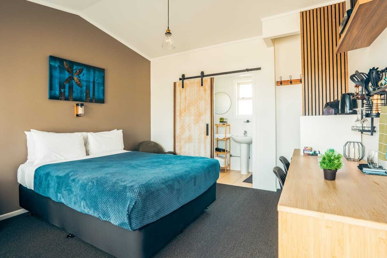 Habitación de hotel moderna con cama, escritorio, lavabo y zona de ducha.