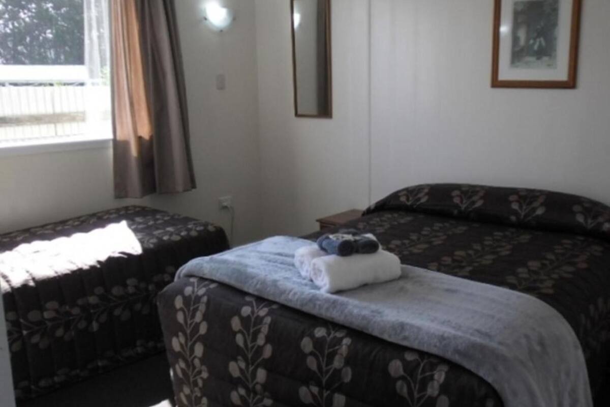 Een slaapkamer met twee eenpersoonsbedden, een groot bed met bloemenmotief, een spiegel en een ingelijst schilderij aan de muur.