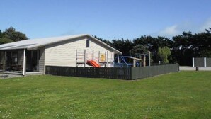 A single-story building with a covered porch and a playground with a slide.