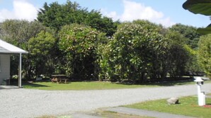A covered outdoor area with a gravel path, a picnic table, and a white lamp post.