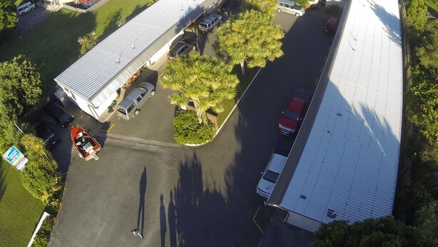 An aerial view of a commercial building with a large parking lot, adjacent to a beach.