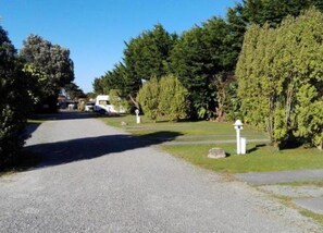 A gravel driveway leading to a campsite with RVs parked.