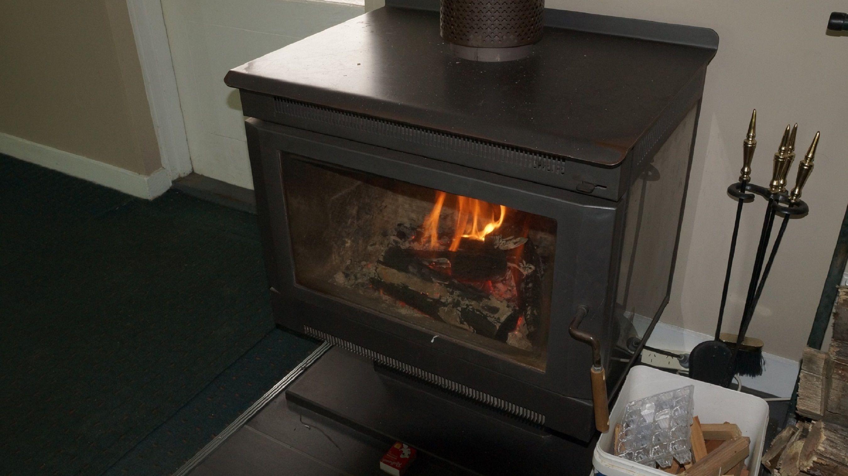 A wood-burning stove with a glass door, a metal top, and a handle.