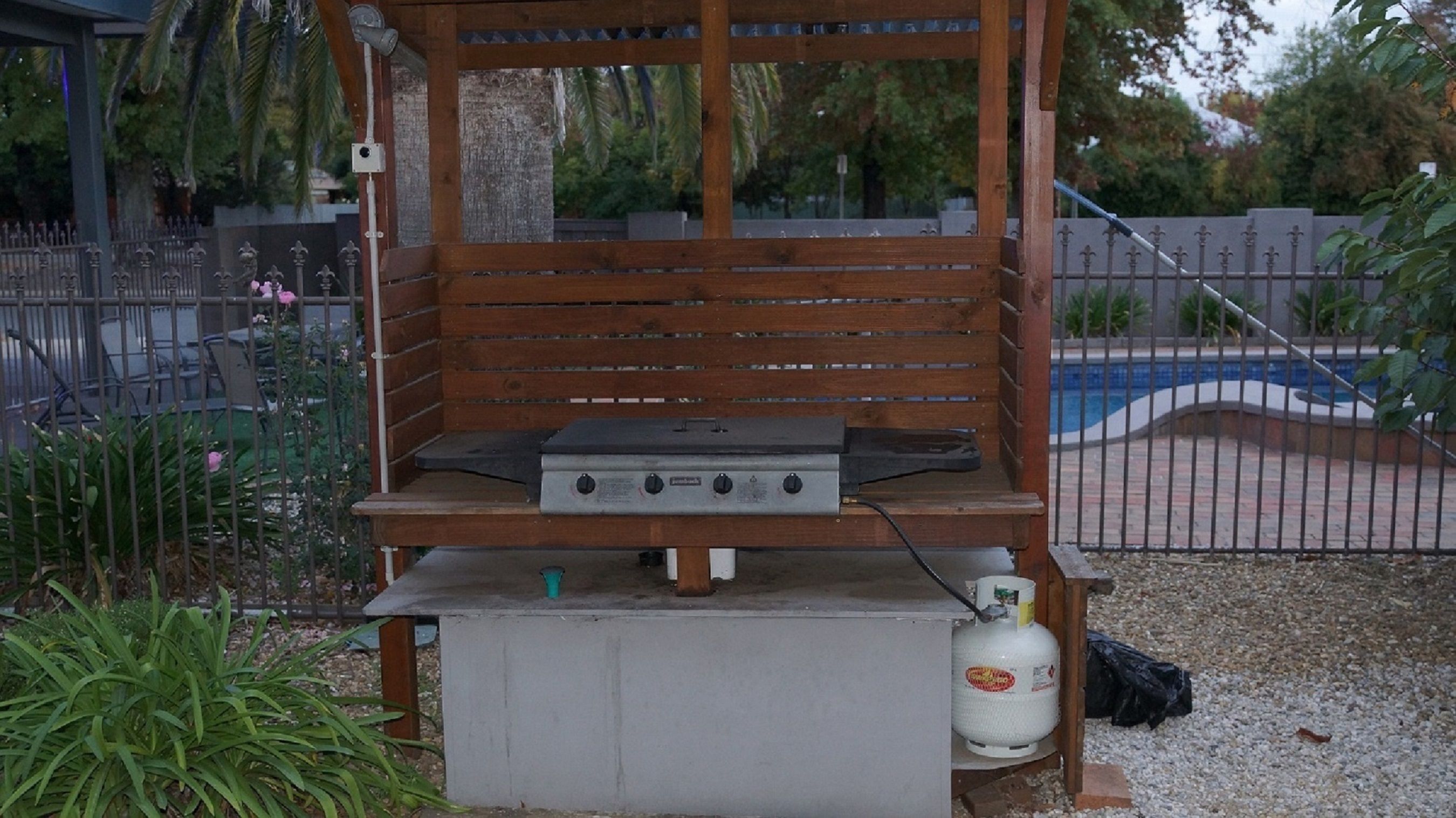 An outdoor grill setup with a gas tank and a metal grill.