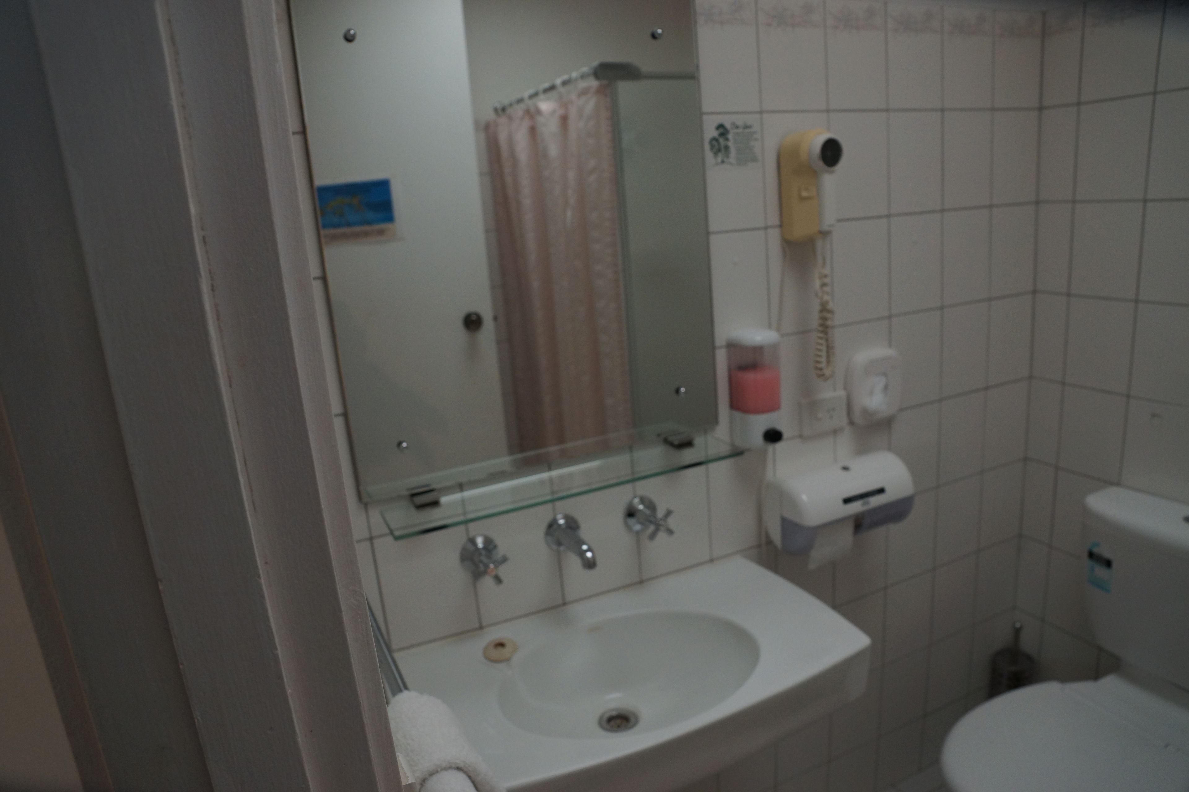Un baño con lavabo, espejo e inodoro.