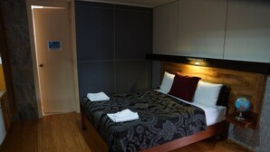 Una habitación de hotel con cama, mesita de noche, un globo terráqueo y una puerta.