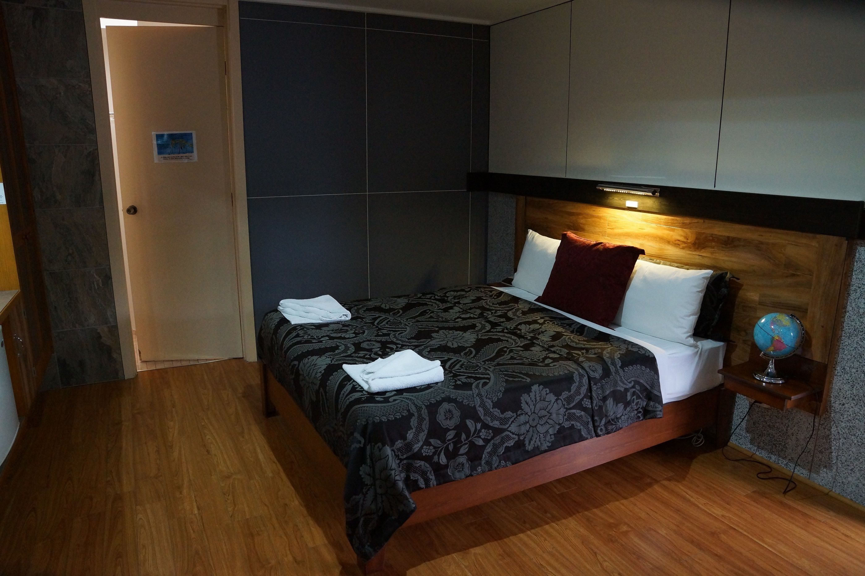 A hotel room with a bed, a nightstand, a globe, and a door.