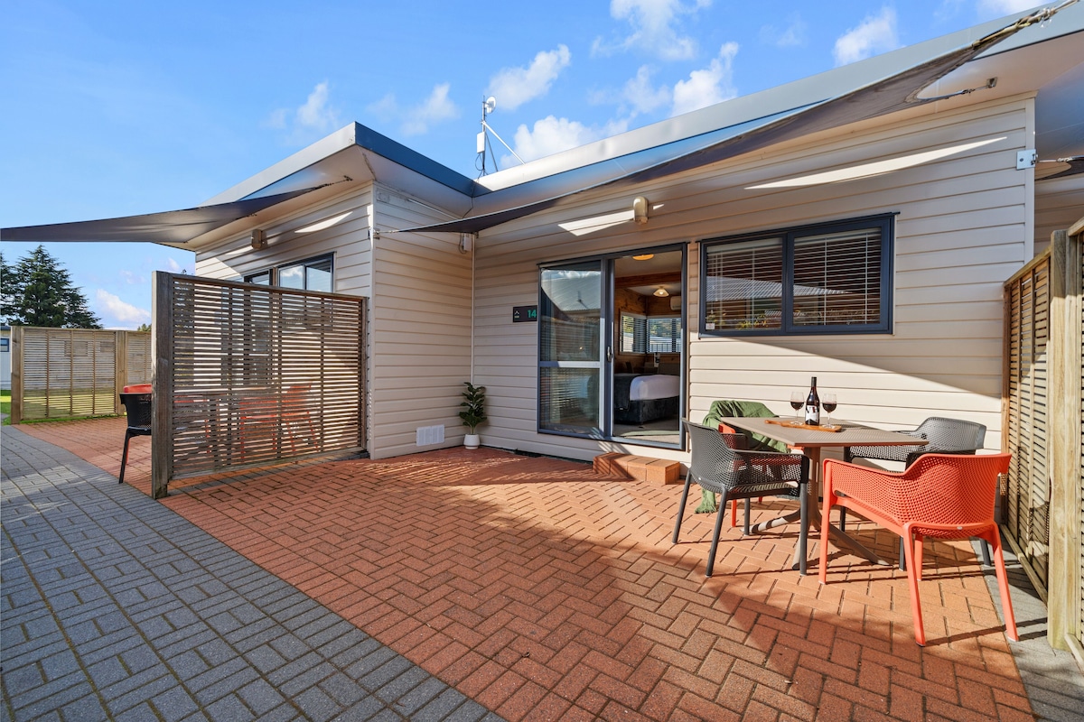 A modern house with a patio area featuring a table and chairs, a sliding glass door, and a covered outdoor space.
