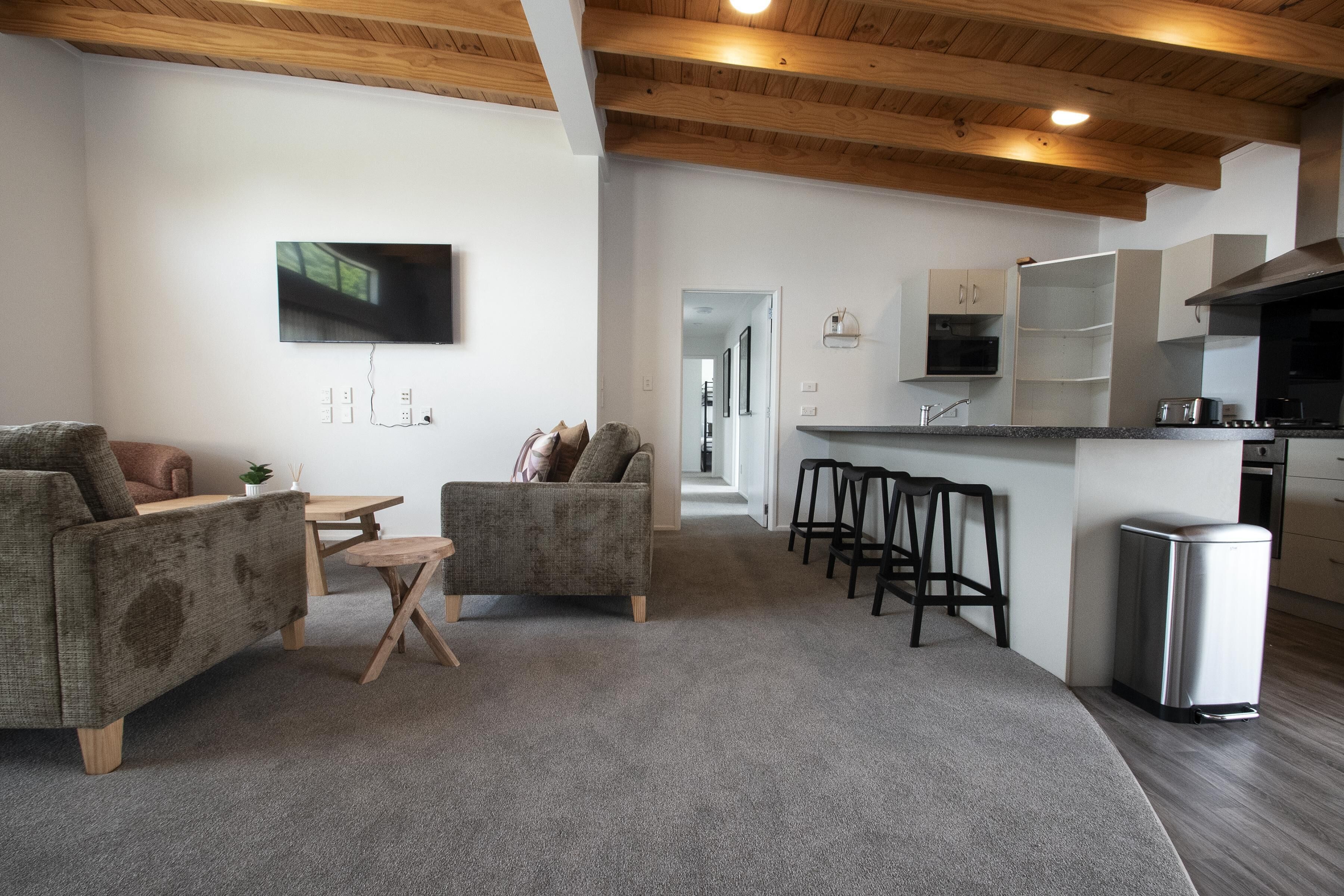 A modern living room with a sofa, a coffee table, and a TV mounted on the wall.