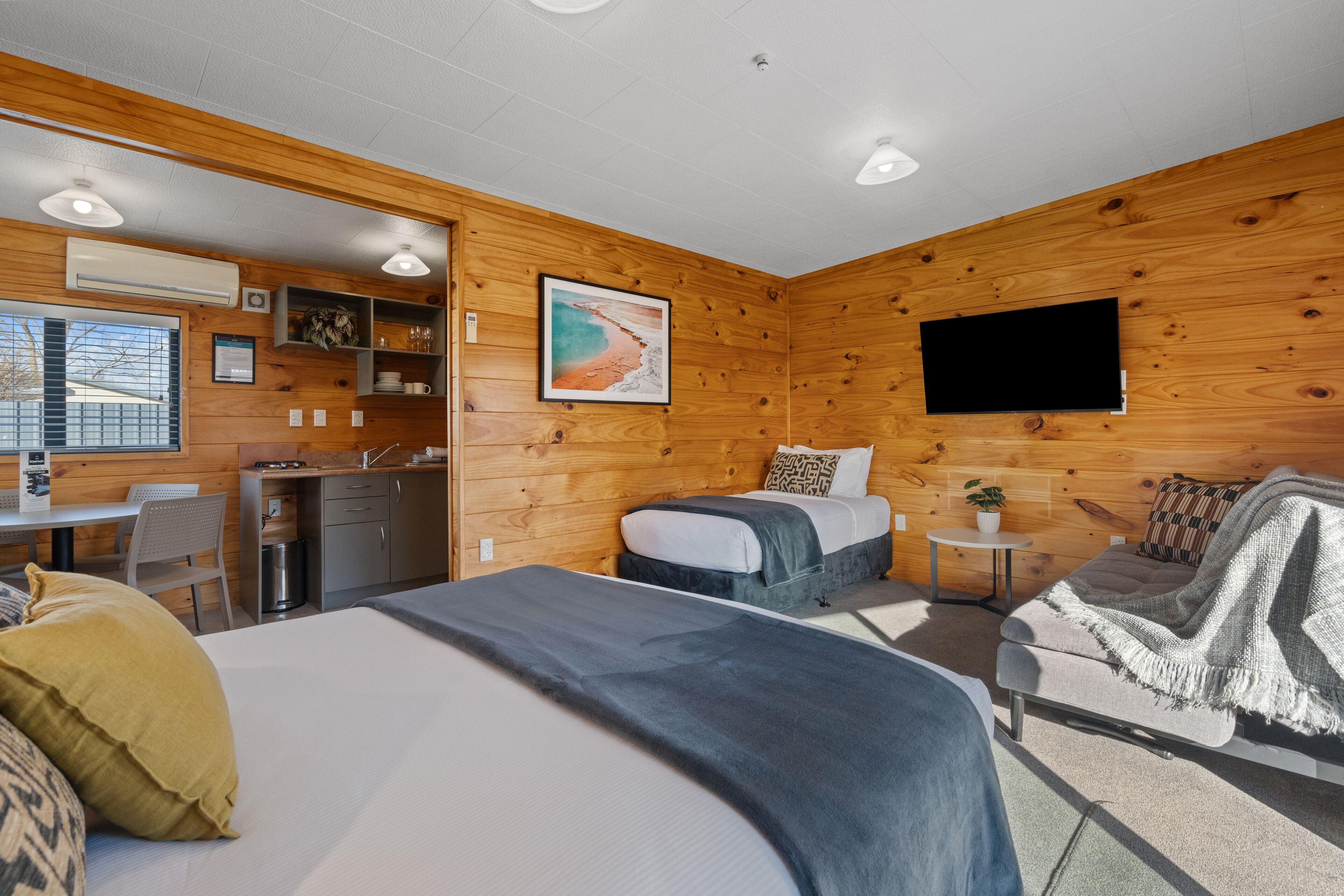Ein gemütliches Blockhauszimmer mit Bett, Sofa, Schreibtisch und Fernseher.